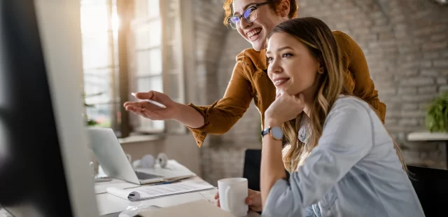 happy-female-entrepreneurs-reading-email-computer-while-working-together-office-focus-is-redhead-woman